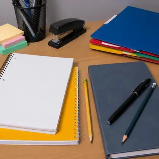 Notebooks, pens and stapler on a desk
